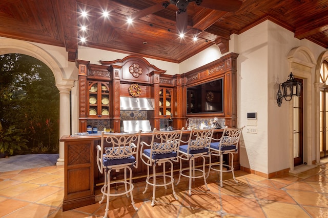 bar featuring wooden ceiling, ornamental molding, range hood, beam ceiling, and decorative columns