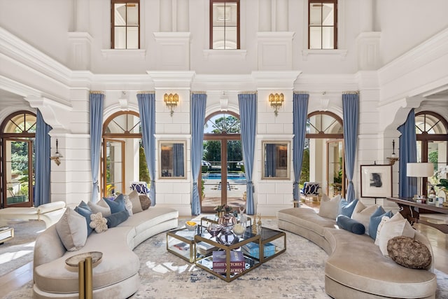 living room featuring a towering ceiling, decorative columns, and a wealth of natural light