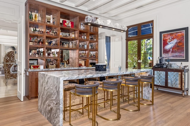 bar featuring french doors, light stone counters, beamed ceiling, crown molding, and light wood-type flooring