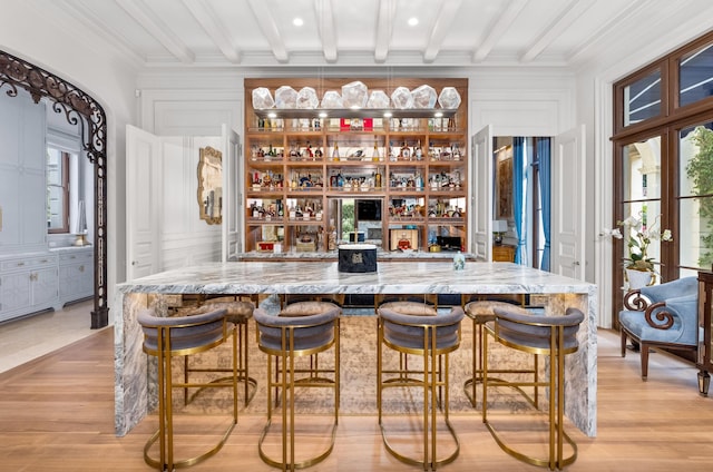 bar with light hardwood / wood-style floors, crown molding, beam ceiling, and a wealth of natural light