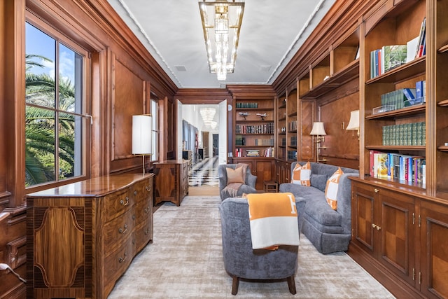 living area featuring built in shelves, crown molding, plenty of natural light, and an inviting chandelier