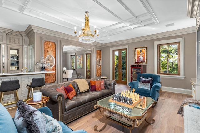 living room featuring a chandelier, ornamental molding, light hardwood / wood-style floors, and coffered ceiling