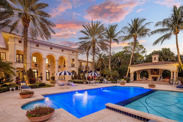 pool at dusk with a patio area