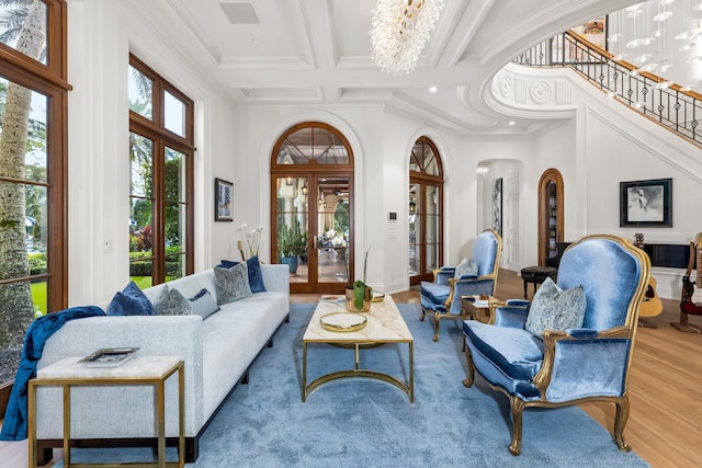 living room featuring an inviting chandelier, coffered ceiling, french doors, beamed ceiling, and light hardwood / wood-style floors