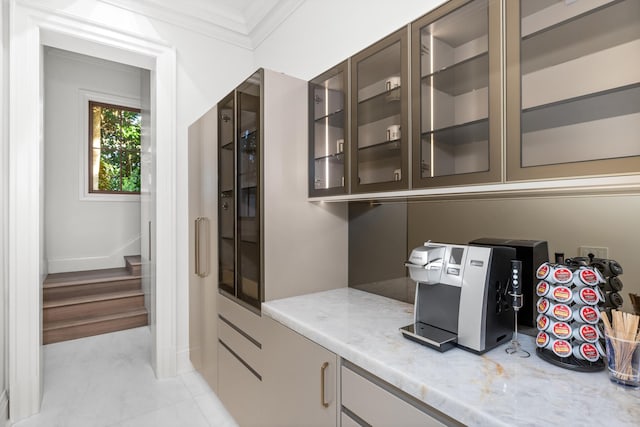 bar with dark brown cabinetry, crown molding, light stone countertops, and light hardwood / wood-style floors