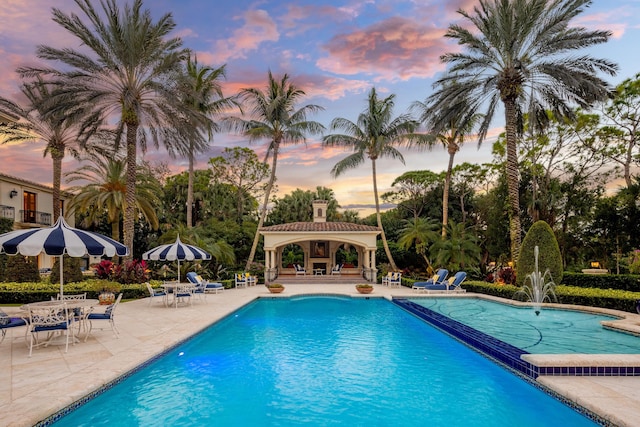 pool at dusk featuring a patio area