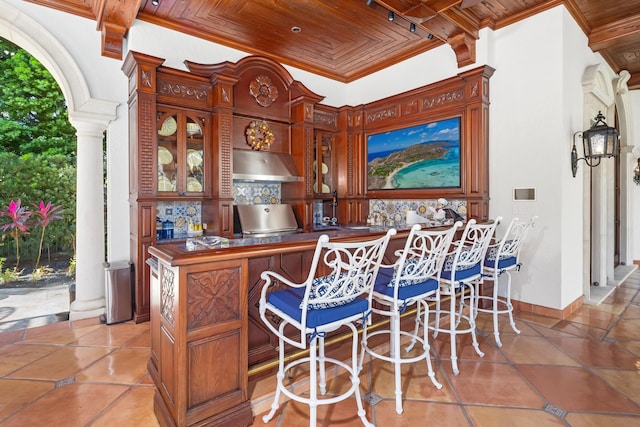 interior space featuring wooden ceiling, crown molding, exhaust hood, and decorative columns