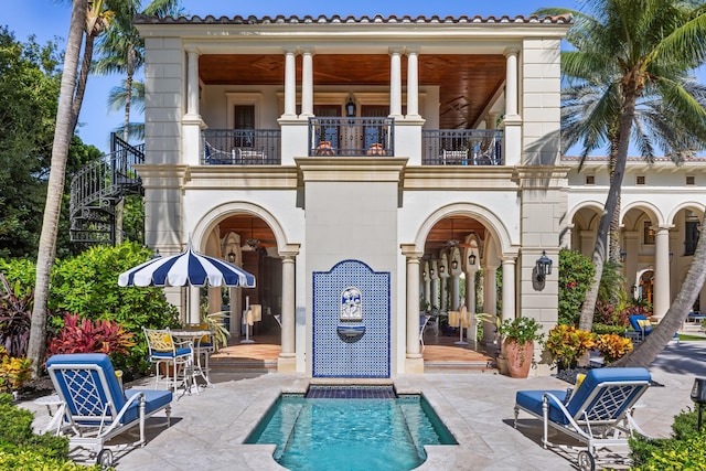 rear view of house with a patio area, a balcony, and a swimming pool