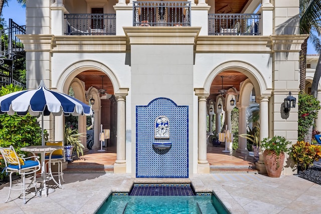 view of exterior entry with a balcony and a patio