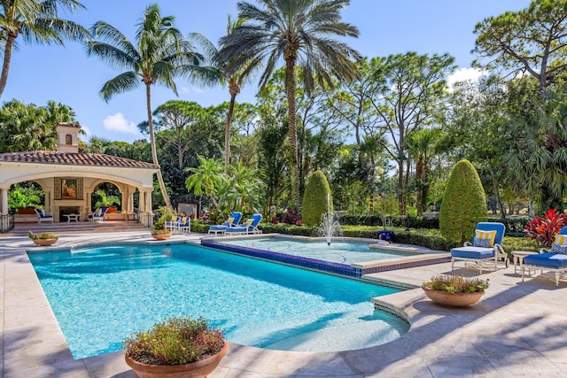 view of swimming pool with pool water feature, exterior fireplace, and a patio area