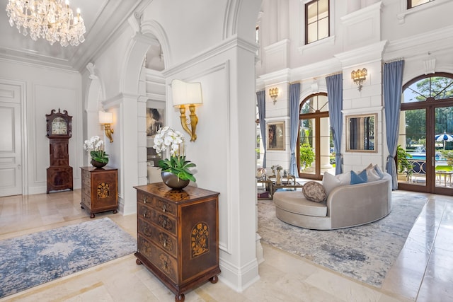 interior space with a high ceiling, french doors, crown molding, ornate columns, and a chandelier