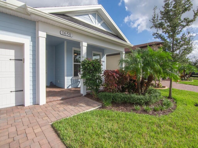 entrance to property featuring a yard, a porch, and a garage