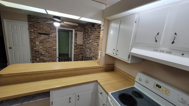 kitchen featuring brick wall, extractor fan, ceiling fan, range, and white cabinetry