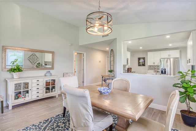 dining room with vaulted ceiling, an inviting chandelier, and light hardwood / wood-style flooring