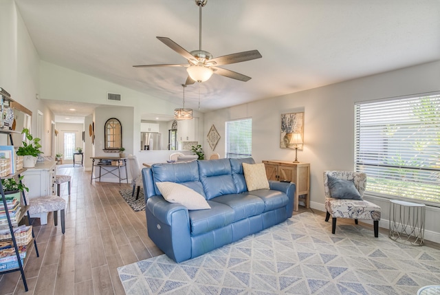 living room featuring ceiling fan, light hardwood / wood-style floors, and vaulted ceiling