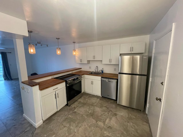 kitchen featuring appliances with stainless steel finishes, decorative light fixtures, white cabinetry, and sink