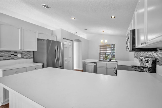 kitchen with pendant lighting, sink, appliances with stainless steel finishes, tasteful backsplash, and kitchen peninsula