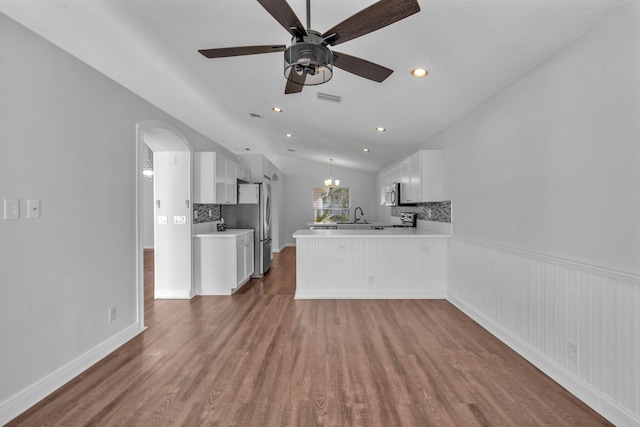 kitchen with white cabinets, dark hardwood / wood-style floors, kitchen peninsula, and vaulted ceiling