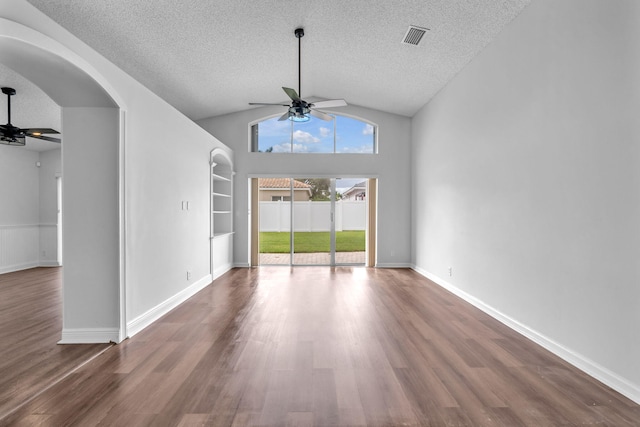 empty room featuring dark hardwood / wood-style flooring, built in shelves, a textured ceiling, ceiling fan, and lofted ceiling