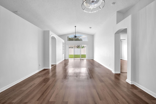 unfurnished living room featuring a notable chandelier, dark hardwood / wood-style flooring, a textured ceiling, and vaulted ceiling