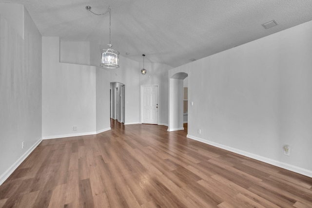 unfurnished living room featuring a textured ceiling, vaulted ceiling, and hardwood / wood-style flooring