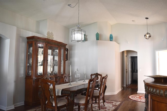 dining room with high vaulted ceiling, dark wood-type flooring, and a notable chandelier