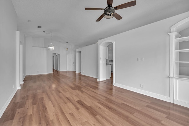 unfurnished living room with ceiling fan, lofted ceiling, a textured ceiling, and light hardwood / wood-style flooring