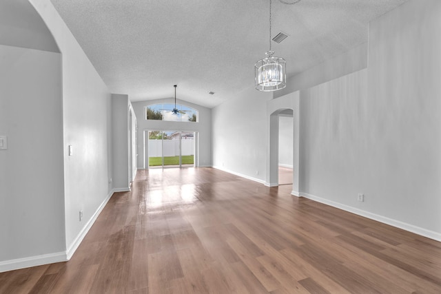 unfurnished room featuring wood-type flooring, a textured ceiling, an inviting chandelier, and lofted ceiling