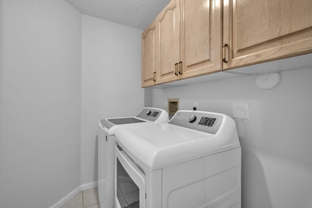 laundry room with light tile patterned flooring, cabinets, a textured ceiling, and independent washer and dryer