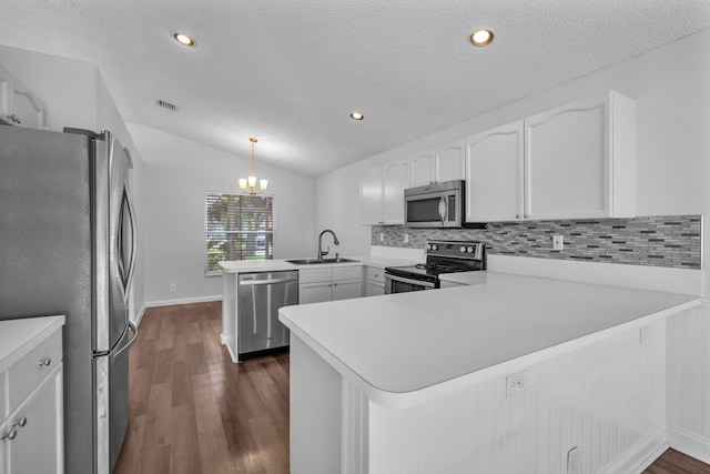 kitchen with lofted ceiling, hanging light fixtures, dark hardwood / wood-style flooring, kitchen peninsula, and stainless steel appliances