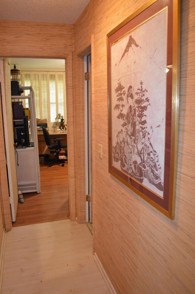 hallway featuring a textured ceiling, hardwood / wood-style flooring, and wood walls