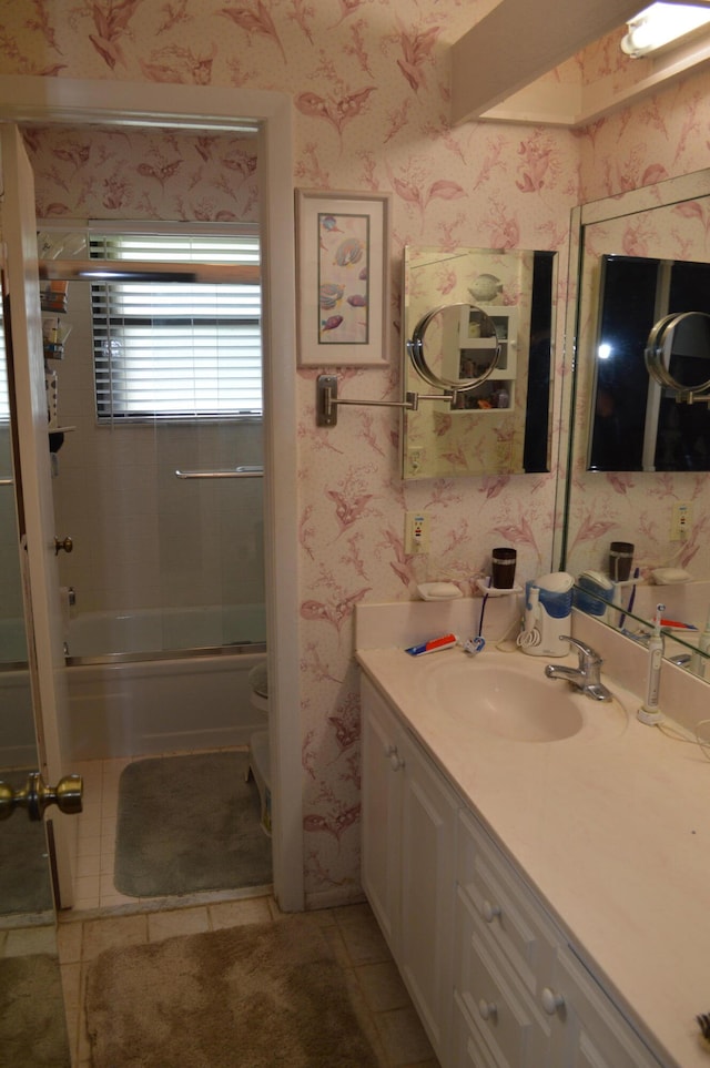 bathroom featuring tile patterned flooring, vanity, and combined bath / shower with glass door