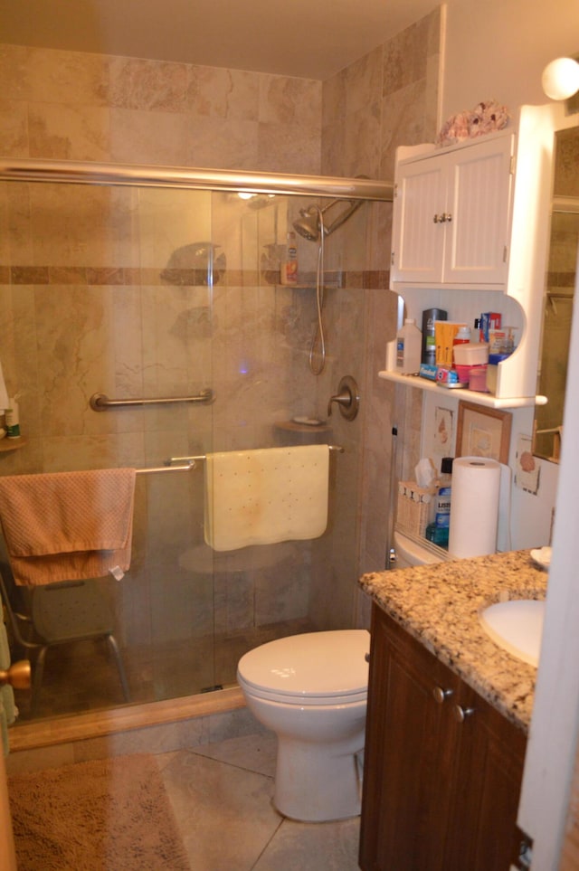 bathroom with tile patterned flooring, vanity, toilet, and a shower with door