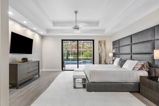 bedroom featuring access to outside, a raised ceiling, ceiling fan, and light wood-type flooring