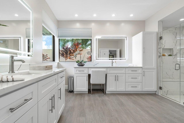 bathroom with hardwood / wood-style floors, vanity, and a shower with shower door