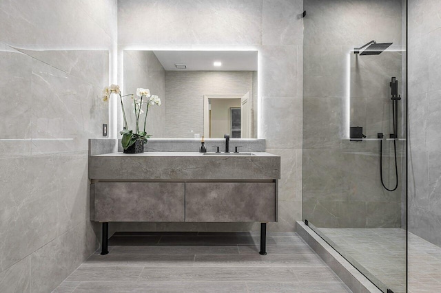 bathroom featuring hardwood / wood-style flooring, vanity, tiled shower, and tile walls