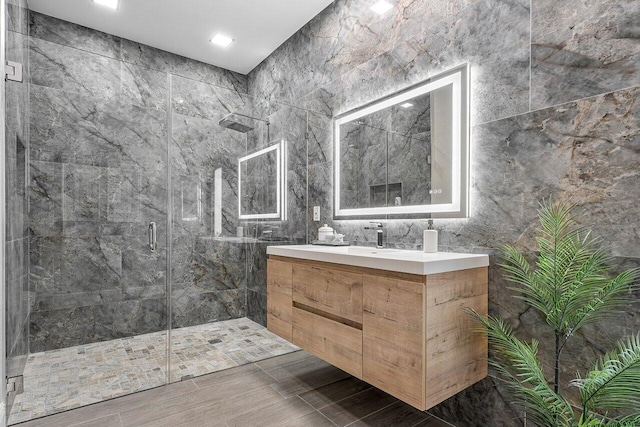 bathroom with vanity, a shower with shower door, and tile walls