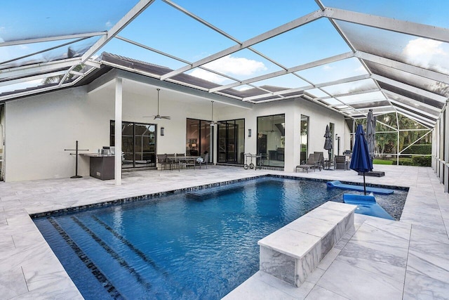 view of swimming pool featuring a patio, glass enclosure, and ceiling fan