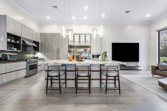 kitchen featuring light stone countertops, extractor fan, decorative light fixtures, a kitchen bar, and stainless steel stove