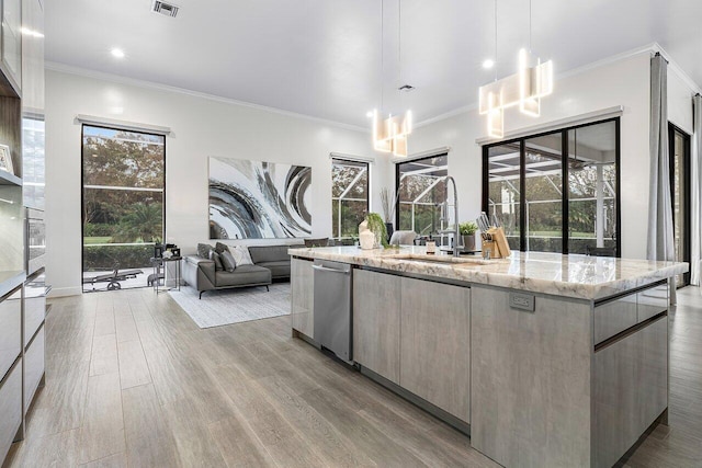 kitchen with light stone countertops, crown molding, pendant lighting, light hardwood / wood-style floors, and a kitchen island with sink