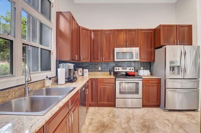 kitchen with decorative backsplash, sink, light stone countertops, and appliances with stainless steel finishes