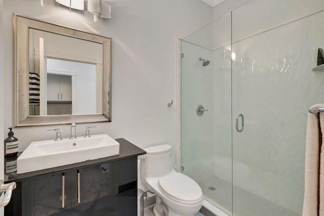 bathroom featuring a shower with door, vanity, and toilet