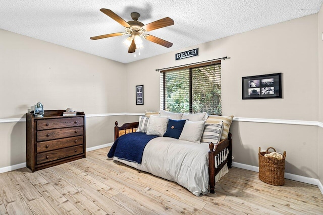 bedroom with a textured ceiling, light wood-type flooring, and ceiling fan