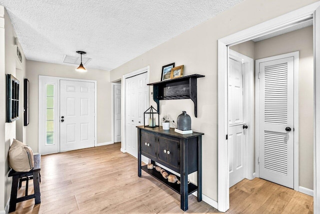 foyer entrance with a textured ceiling and light wood-type flooring