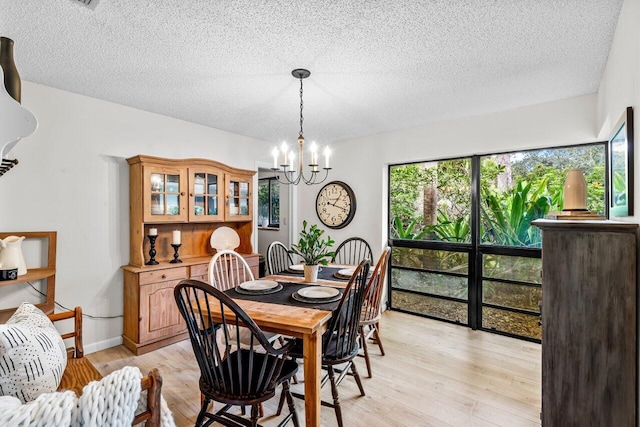 dining area featuring a textured ceiling, light hardwood / wood-style floors, and a notable chandelier