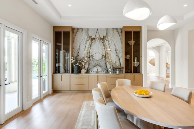 dining room featuring arched walkways, recessed lighting, and light wood-style floors