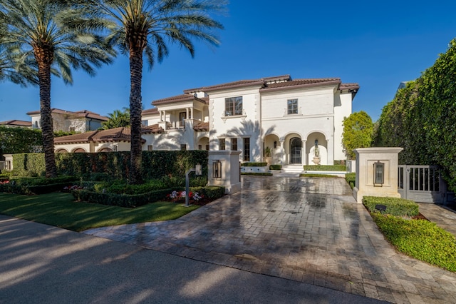 mediterranean / spanish home with stucco siding, fence, a balcony, and a gate