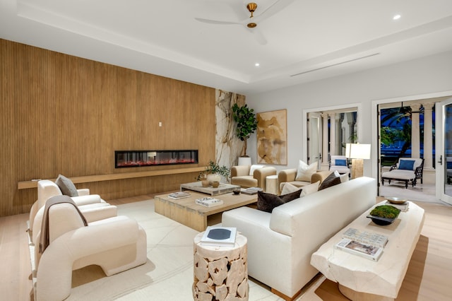 living room with recessed lighting, a glass covered fireplace, and wood walls
