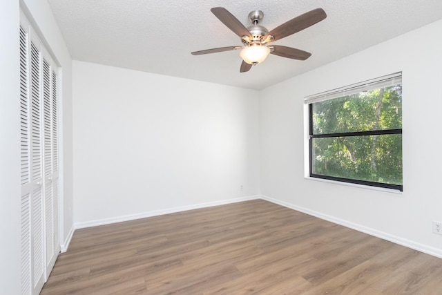 unfurnished bedroom featuring ceiling fan, a closet, wood-type flooring, and a textured ceiling