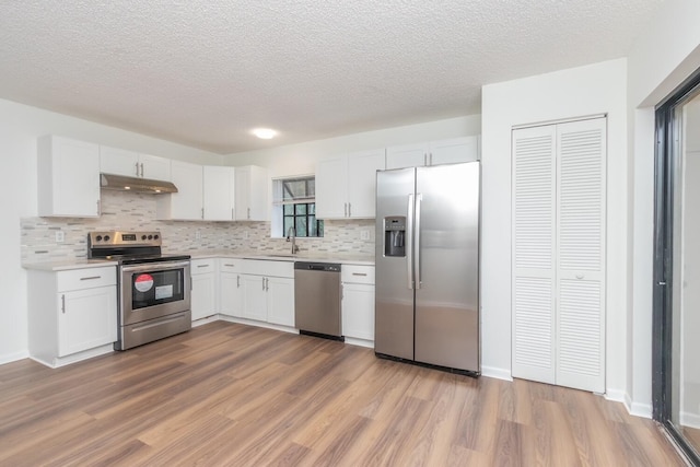 kitchen featuring decorative backsplash, appliances with stainless steel finishes, sink, wood-type flooring, and white cabinets